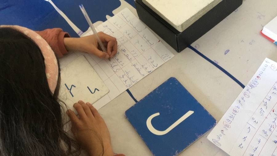 Une élève écrit des lettres arabes